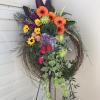 Colorful floral wreath on a stand with orange, purple, yellow, and pink blooms
