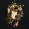 Floral wreath with a prayer card and mixed blooms on a dark background