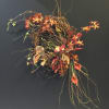 Abstract floral wreath with orange blooms and trailing vines on a dark background