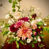 Airy arrangement of peach dahlias with pink and white roses in a low vase on a wooden table