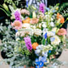 Loose hand-tied bouquet of colorful mixed flowers in purple, blue, white, and orange tones