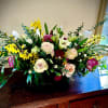 Low centerpiece of ivory roses, white lilies, yellow blooms and pink flowers in a black rectangular vase