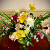 Mixed bouquet with yellow daffodils, pink roses, and white blooms in a round vase on a wooden table