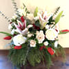 Arrangement of white roses, blush lilies, and red tulips in a clear vase with cascading greenery.
