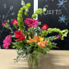Mixed bouquet with roses, gerbera daisies, and orange alstroemeria in a glass vase