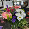 Mixed bouquet with pink gerberas, white daisies, and purple filler flowers in a glass vase
