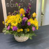 Basket arrangement of yellow daisies, purple flowers, and yellow roses
