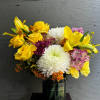 Bouquet of yellow roses, white chrysanthemums, and lilies in a glass vase