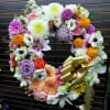 Heart-shaped floral wreath with mixed blooms and a gold ribbon bow