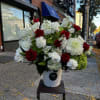 Red roses and white flowers arranged in a white bucket on a stand