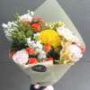 Bouquet of yellow, orange, and white flowers wrapped in pale paper