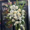 Tall white floral standing arrangement with roses, daisies, and calla lilies