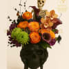 Halloween floral arrangement in a black skull vase with a skeleton topper