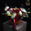 Red and white rose arrangement in an orange pumpkin vase with ribbon