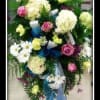 Fresh floral funeral arrangement with roses, hydrangea, and other flowers.