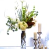 In a tall clear glass cylinder, magnolias or seasonal greens, hydrangeas, curly