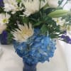 Blue hydrangeas, white asters, white daisies, white lilies, white roses and purple