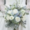 Soft blue delphinium, white roses, white lisianthus and more fill this elegant
