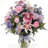 Beautiful stargazer lilies in a glass vase with pink carnations, lavender daisies