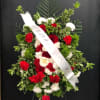 A funeral spray that is filled with red and white roses/carnations and