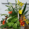 A large white basket arrangement of summer vegetables and assorted flowers in