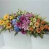 A TRANQUIL CASKET SPRAY WITH YELLOW, ORANGE, PURPLE AND LAVENDER TONES.