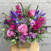 Roses, lisianthus and a succulent in shades of lavender among fuchsia stock