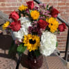 Bright sunflowers, red roses, white hydrangeas, purple wax flower and alstroemeria.