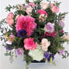 Pinks and purple arrangement in a clear cube vase. 