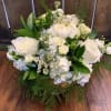 Greens and white elegantly arranged in a pedestal vase  