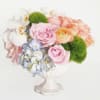 A rainbow of pastel colored flowers in a beautiful white porcelain pedestal