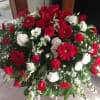 This casket cover is full of red and white flowers snapdragons. Gerbra