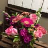 This arrangement includes pink roses, purple stock, hot pink gerbera daisy, peach