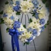 White roses and blue hydrangeas are complimented with white daisies, white Fuji