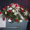 Red roses and white lilies, with silver dollar eucalyptus and greens, reflect
