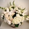 A beautiful compilation of seasonal white flowers in a lovely ceramic antique