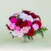 Overflowing in a clear glass footed vase are beautiful garden roses, spray