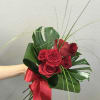 Half a dozen red roses hand tied with tropical greenery is a