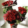 Arrangement of red roses and deep purple cymbidium orchids. 