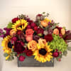 A collection of fall toned flowers in a wood box, the perfect