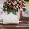 A beautiful casket spray with roses and carnations and various grains