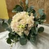A natural hand tied of cream and blush roses accent with white