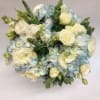 Soft blue hydrangea is mixed with delicate white roses, veronica, stock, and