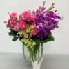 Clear vase for this elegant arrangement toped with ranunculus, orchids, and our