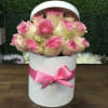 White hat box filled with lush pink roses with a pink satin