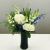 Elegant white flowers with pops of blue in a tall black vase
