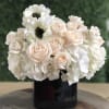 Beautiful floral arrangement of whites in black vase. Anemones are added for