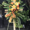 cross easel with river cane, lilies, orange roses, &amp; orchids
