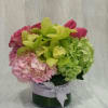 Low and round arrangement composed of hydrangeas, roses, tulips and cymbidium orchids