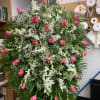 A standing spray consisting of medium pink roses, white dendrobium orchids and